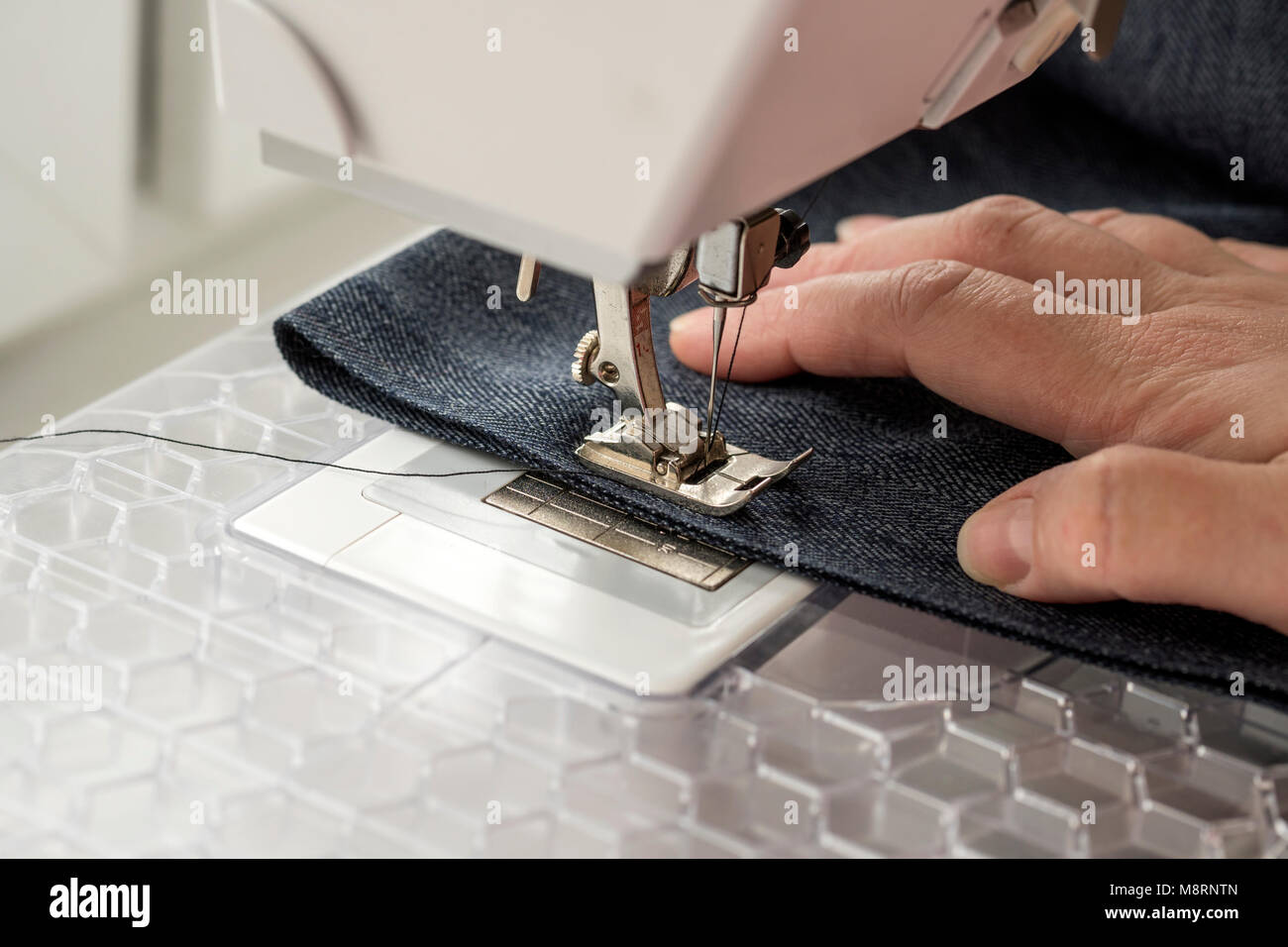 sewing machine sews denim fabric Stock Photo Alamy