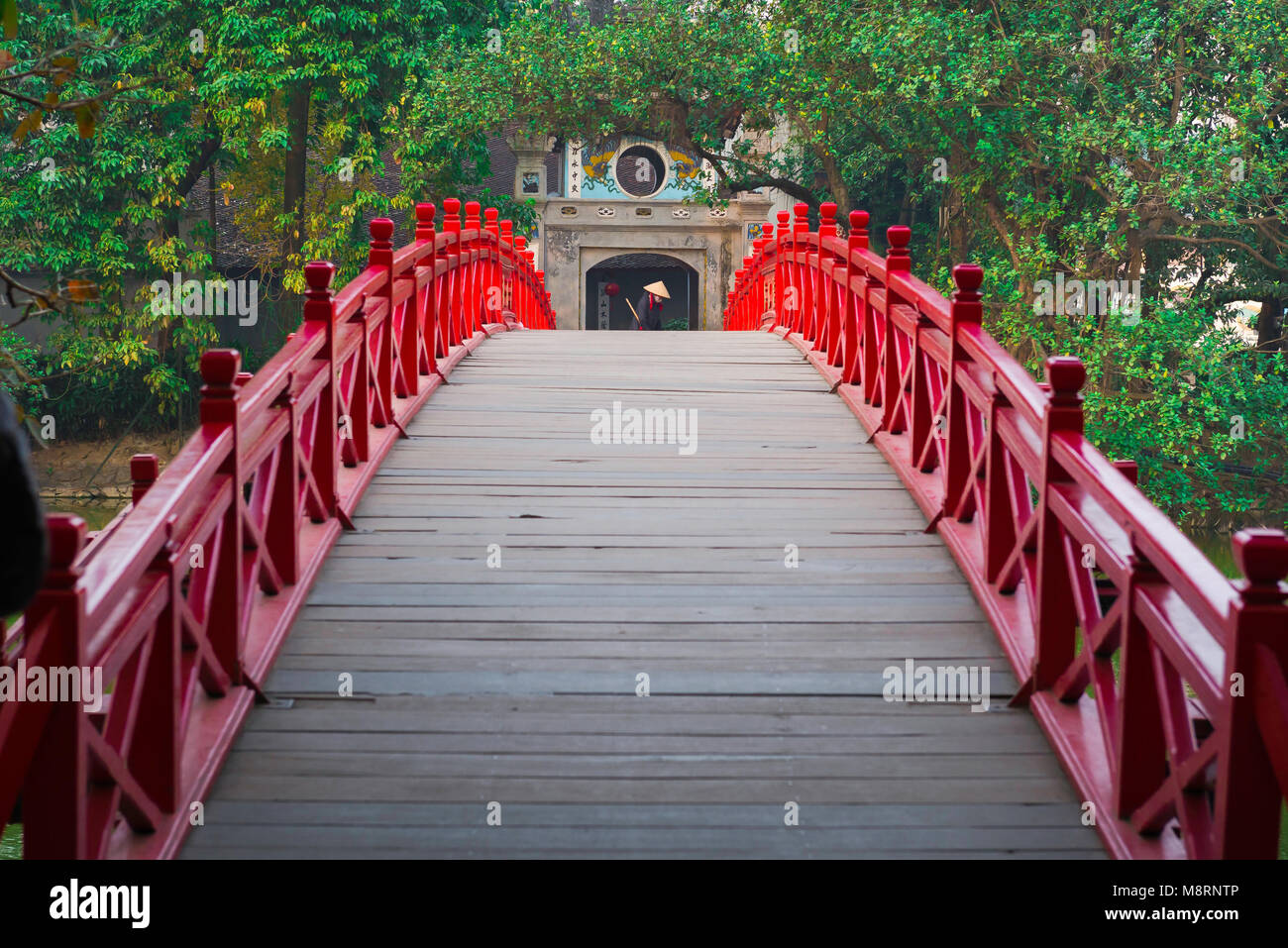 Hanoi bridge, view across the Huc Bridge in Hanoi showing a woman sweeping the entrance to the Temple Of The Jade Mound on Hoan Kiem Lake, Vietnam. Stock Photo