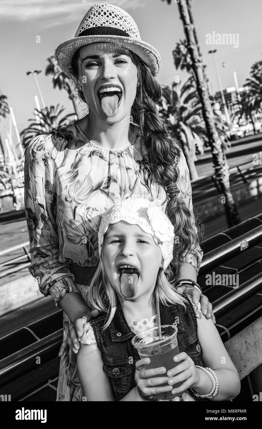 Summertime at colorful Barcelona. smiling stylish mother and child travellers in Barcelona, Spain showing tongues after drinking bright red beverage Stock Photo