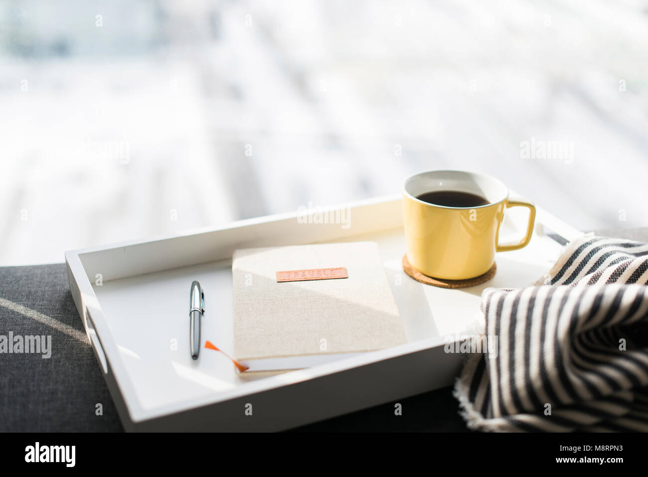 Close-up of diary between pen and coffee cup in tray on sofa Stock Photo