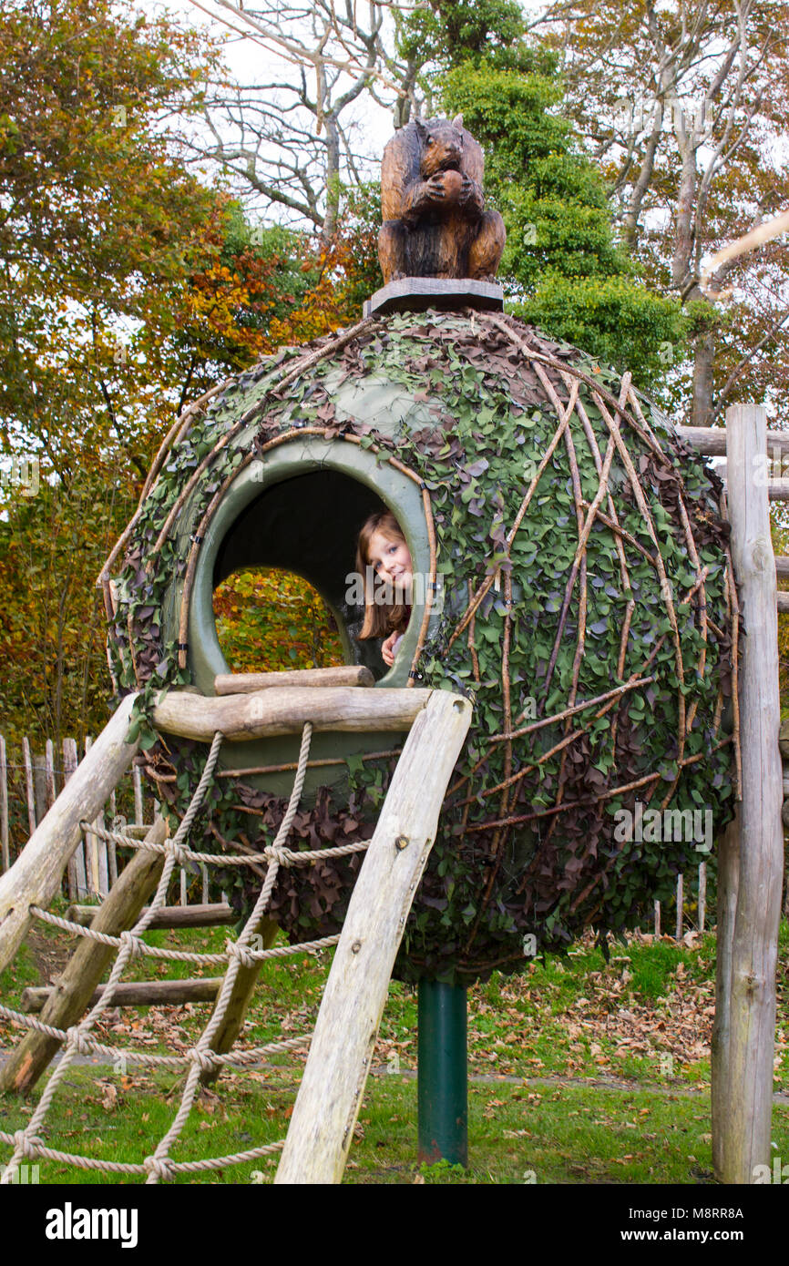 A young girl popping her head out of a coconut climbing frame house in a children's adventure playground in Castlewellan County Down northern Ireland Stock Photo