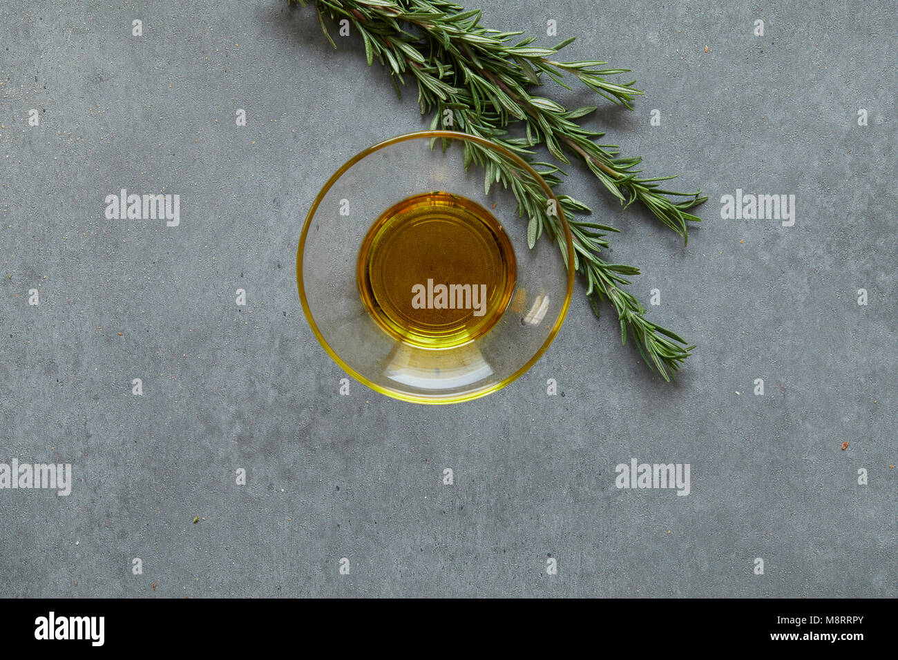 Close-up of rosemary by oil in bowl on concrete table Stock Photo