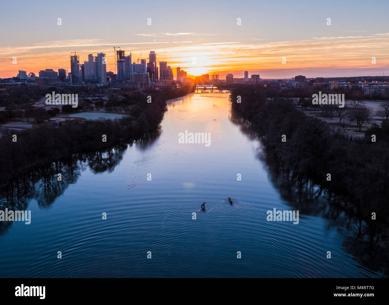 High angle distant view of people sculling on Lady Bird Lake against cityscape during sunrise Stock Photo
