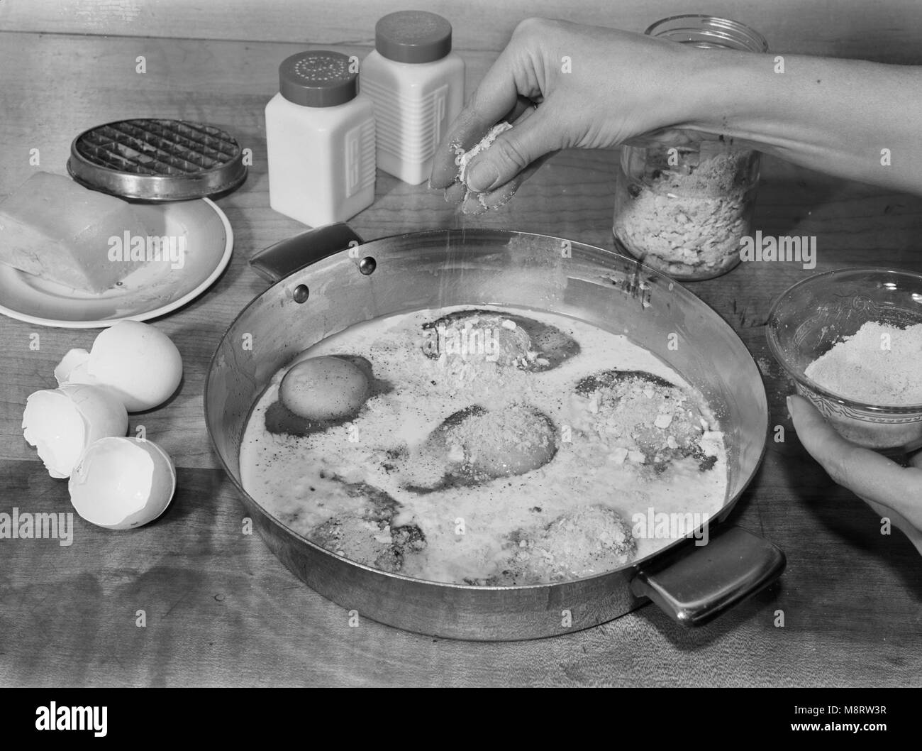 Woman Sprinkling Grated Cheese while Making Baked Eggs with Cheese, A Meat Substitute, Ann Rosener for Office of War Information, October 1942 Stock Photo