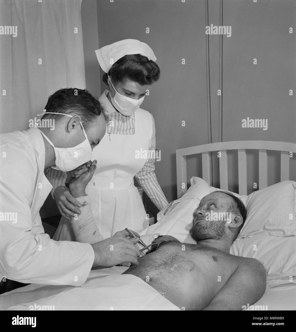 Torpedoed Sailor Receiving Burn Treatment from Doctor and Student Nurse, Susan Petty, Fritz Henle for Office of War Information, November 1942 Stock Photo