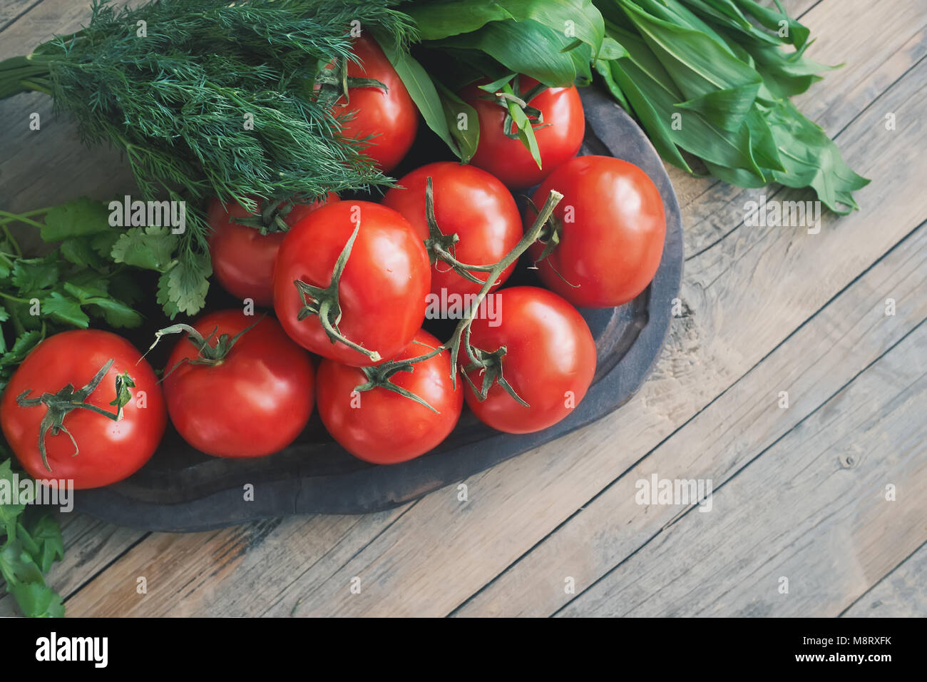 A large branch of ripe red tomatoes on a wooden Board with leaves of ...