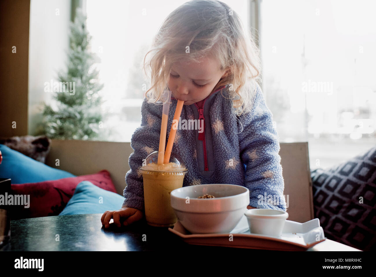 Girl drinking coffee while sitting by window at home Stock Photo