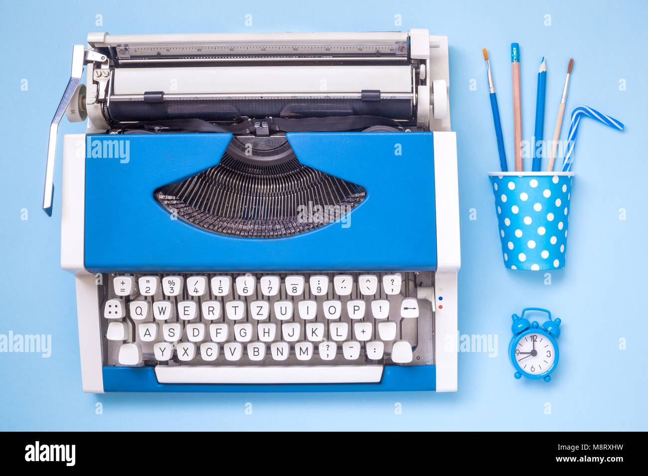 Flat lay of typewriter, office supplies and alarm clock on pastel blue ...