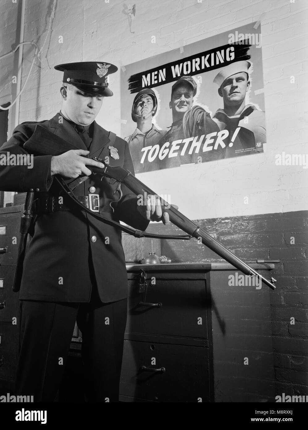 Sentinel Inspecting Rifle as he Keeps Vigil Against Saboteurs at Factory Converted to War Production, White Motor Company, Cleveland, Ohio, USA, Alfred T. Palmer for Office of War Information, December 1941 Stock Photo