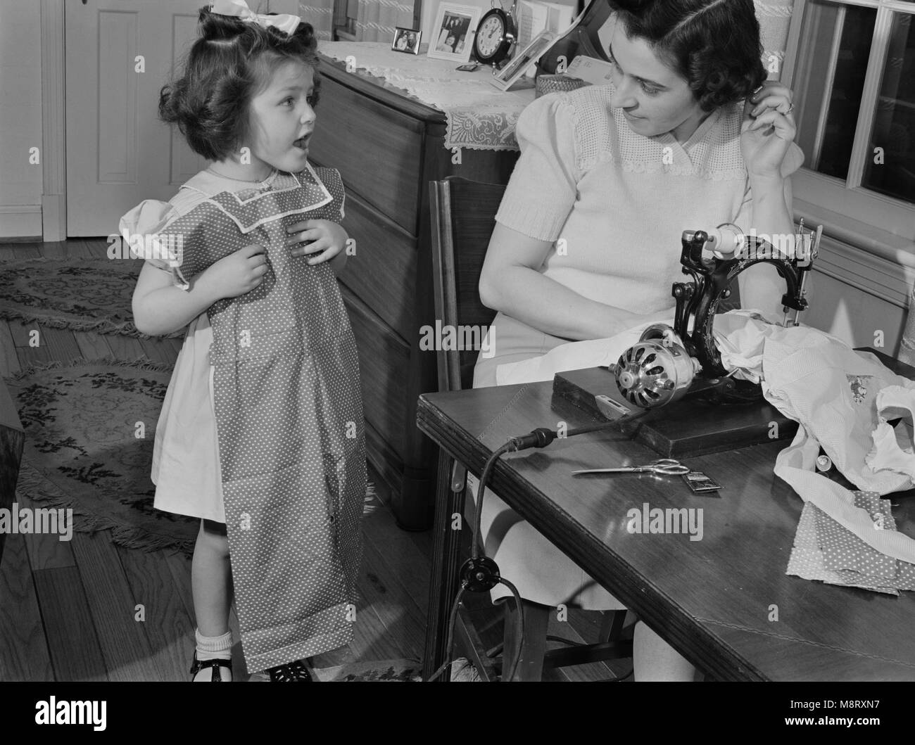 Mother Conserving Clothing by Making Daughter a Playsuit from Old House Dress, as Wool and other Materials are Needed by the Armed Forces, Ann Rosener, Office of War Information, February 1942 Stock Photo