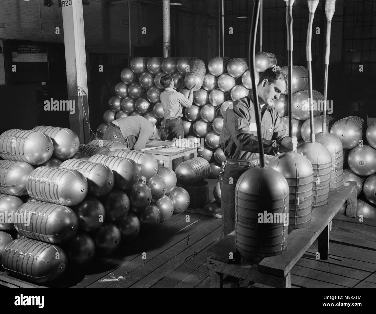 Three Workers Testing and Stacking Shatterproof Oxygen Cylinders for High Altitude Flying Manufactured at Factory Converted to War Production, Firestone Tire and Rubber Company, Akron, Ohio, USA, Alfred T. Palmer for Office of War Information, February 1942 Stock Photo