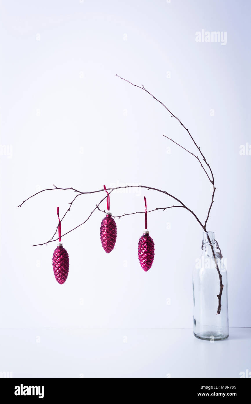Christmas decorations hanging on twig in bottle against white background Stock Photo