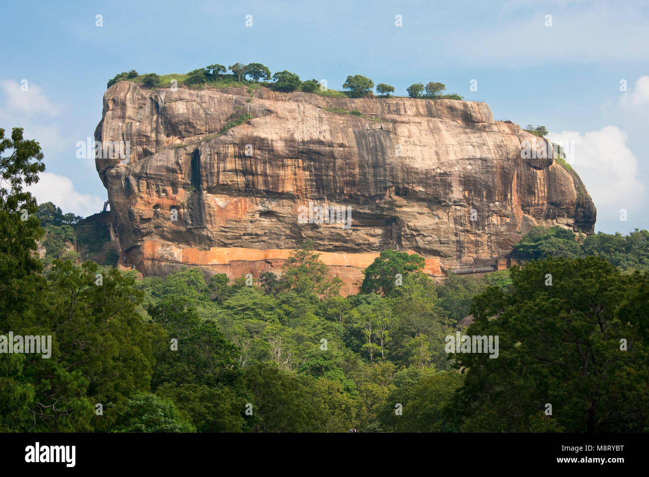 A view of Sigiriya Rock taken from the main public tourist road on a sunny day with blue sky. Stock Photo