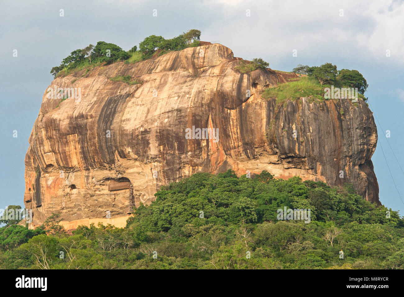 A 'rear' view of Sigiriya Rock taken from a public road on a sunny day with blue sky. Stock Photo