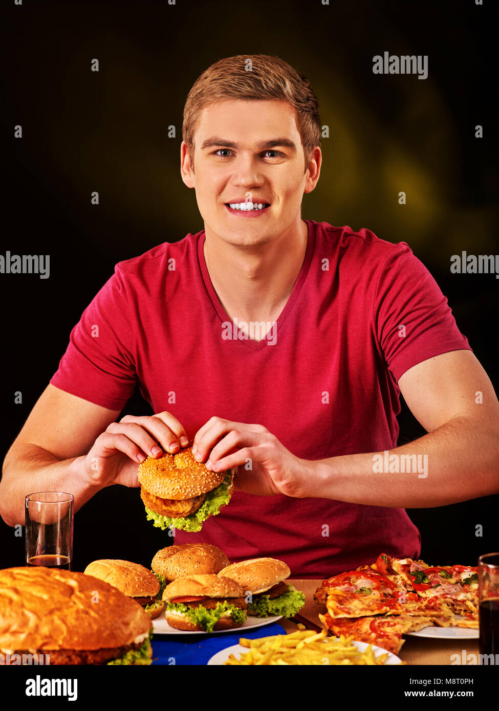 Woman eating french fries and hamburger on table. Stock Photo