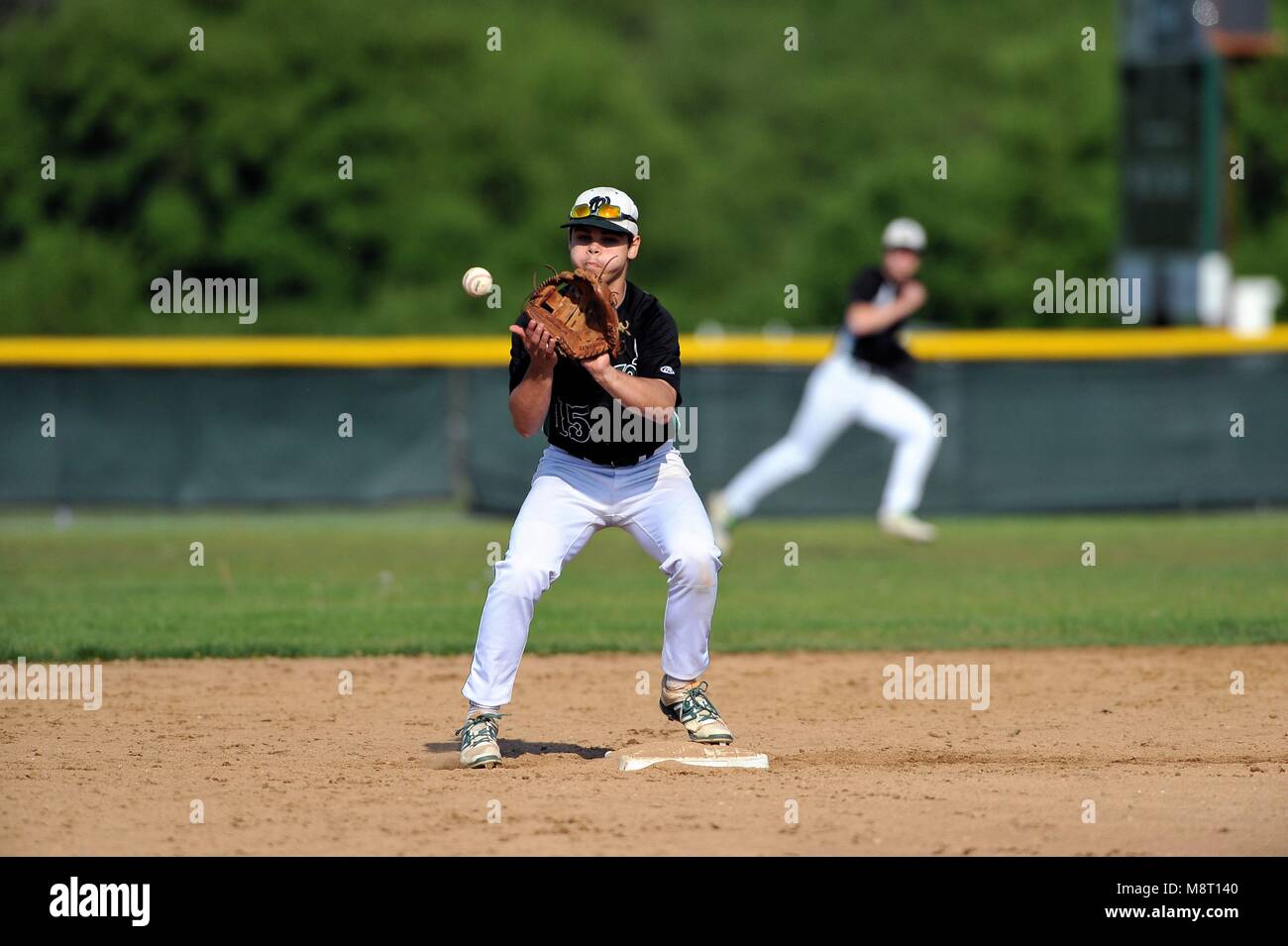 Second baseman taking a throw from his shortstop to retire a runner at second base before relaying on to first base. USA. Stock Photo