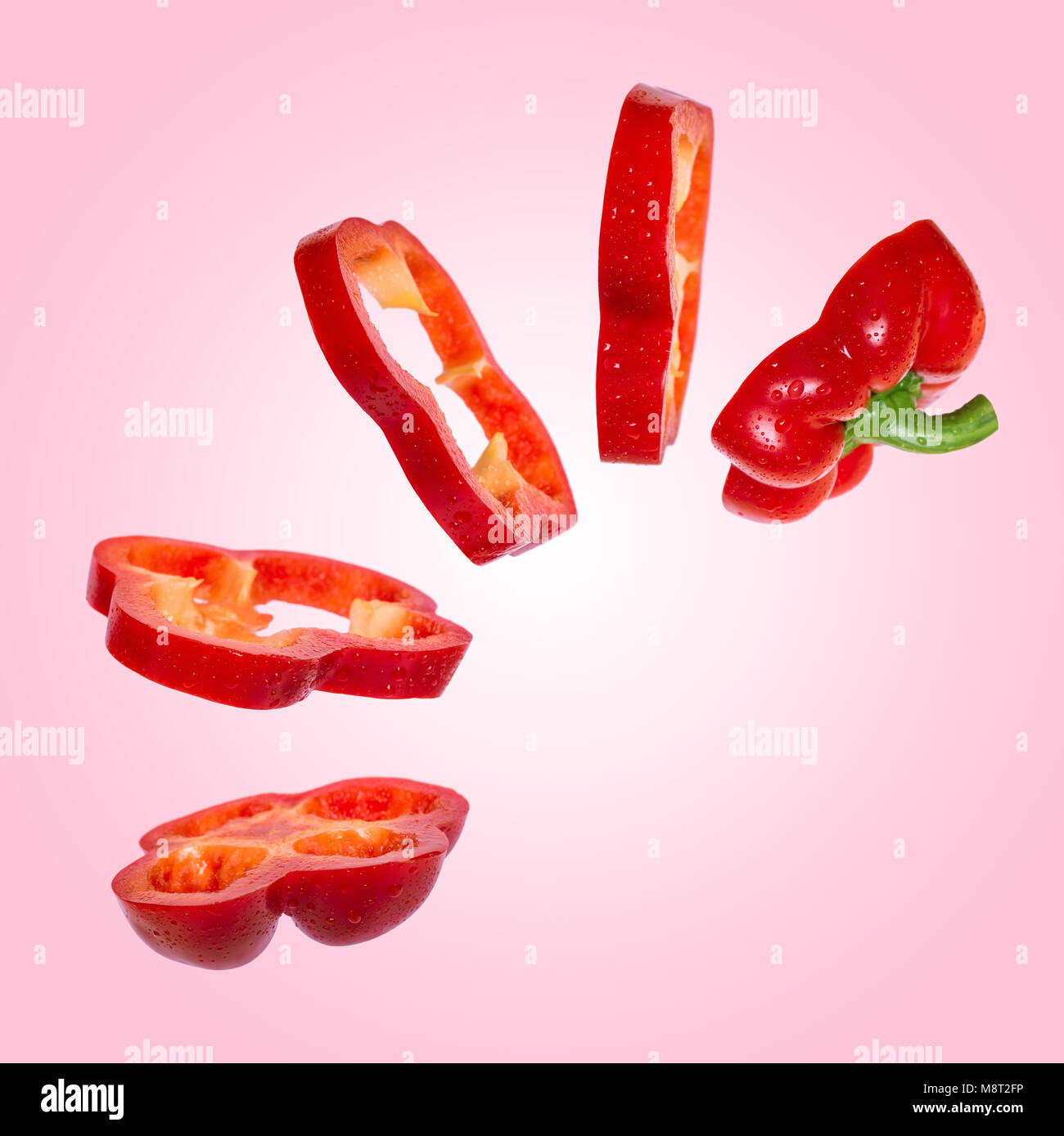 Creative concept with flying red paprika. Sliced floating pepper. Levity capsicum vegetable on pink background Stock Photo