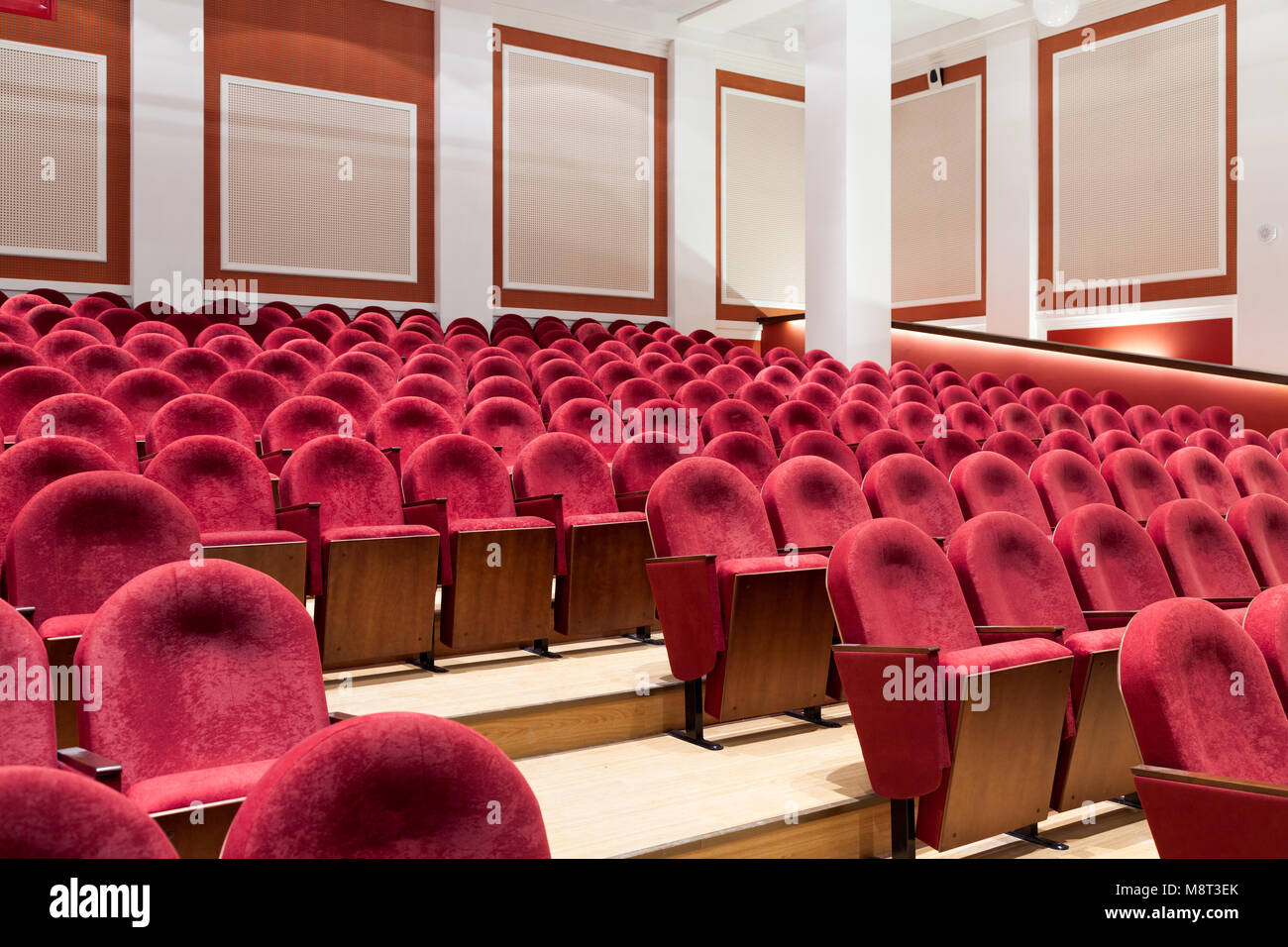 View from stairs on rows of comfortable red chairs in theater or cinema . Curve of Red Seats Stock Photo