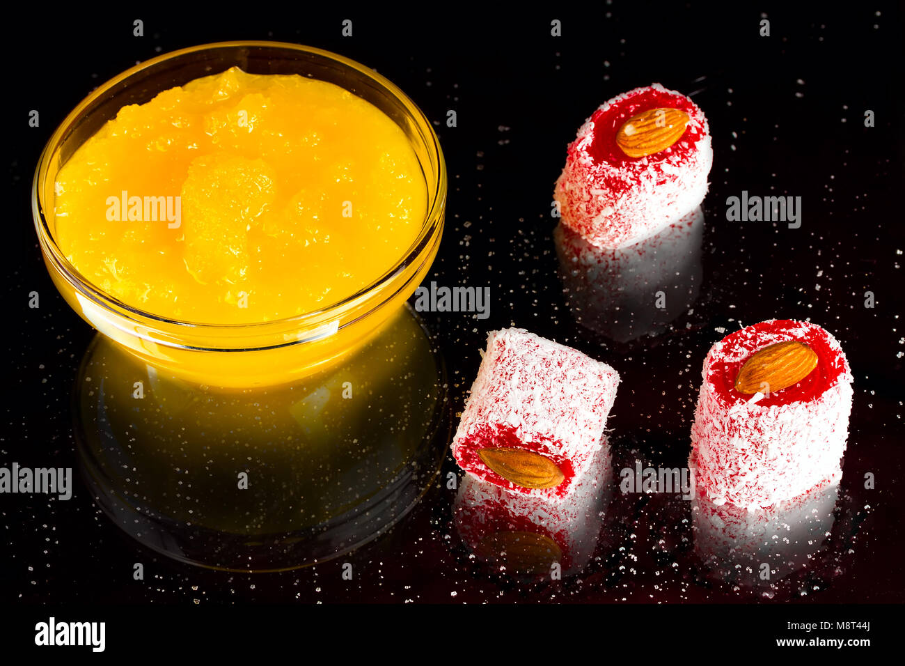 honey, rakhat-lukum sprinkled with coconut shavings and almond on dark background, turkish sweets Stock Photo