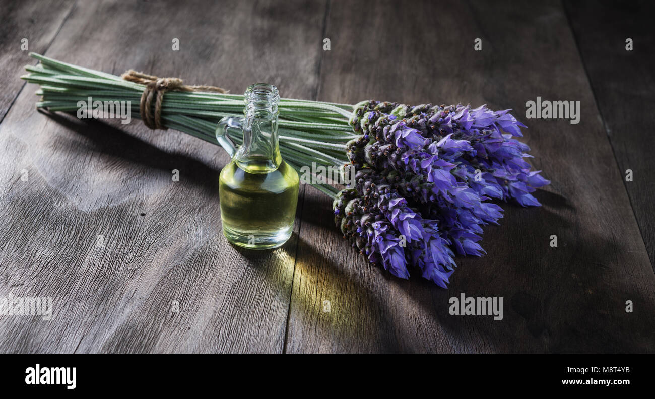 fresh lavender flowers and essential oil as natural aromatherapy for headache and migraine relief on old wooden background Stock Photo