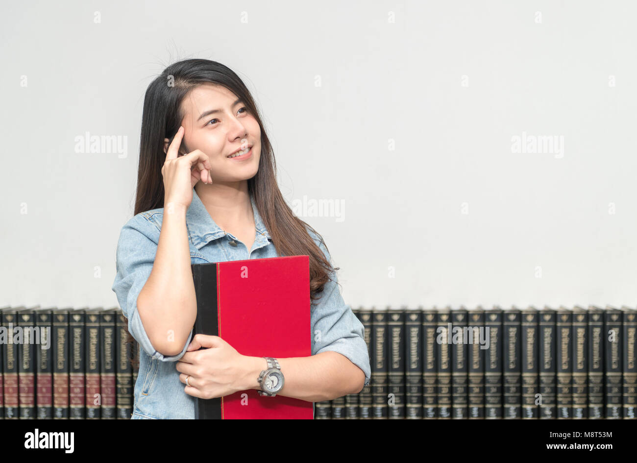 Happy smiling female student posing in the university library, she is ...