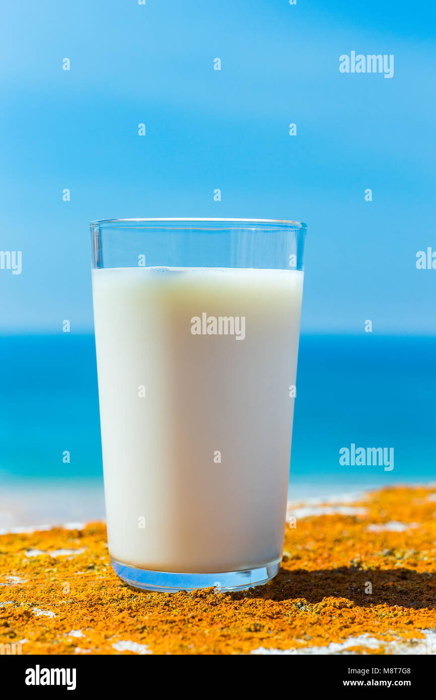 Glass filled with cow milk blue sea and sky Stock Photo