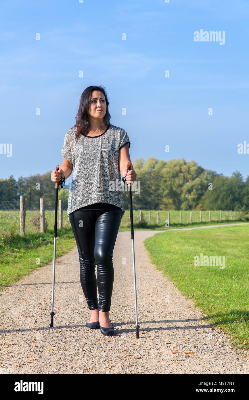 Young woman hiking with Nordic Walking sticks in nature Stock Photo