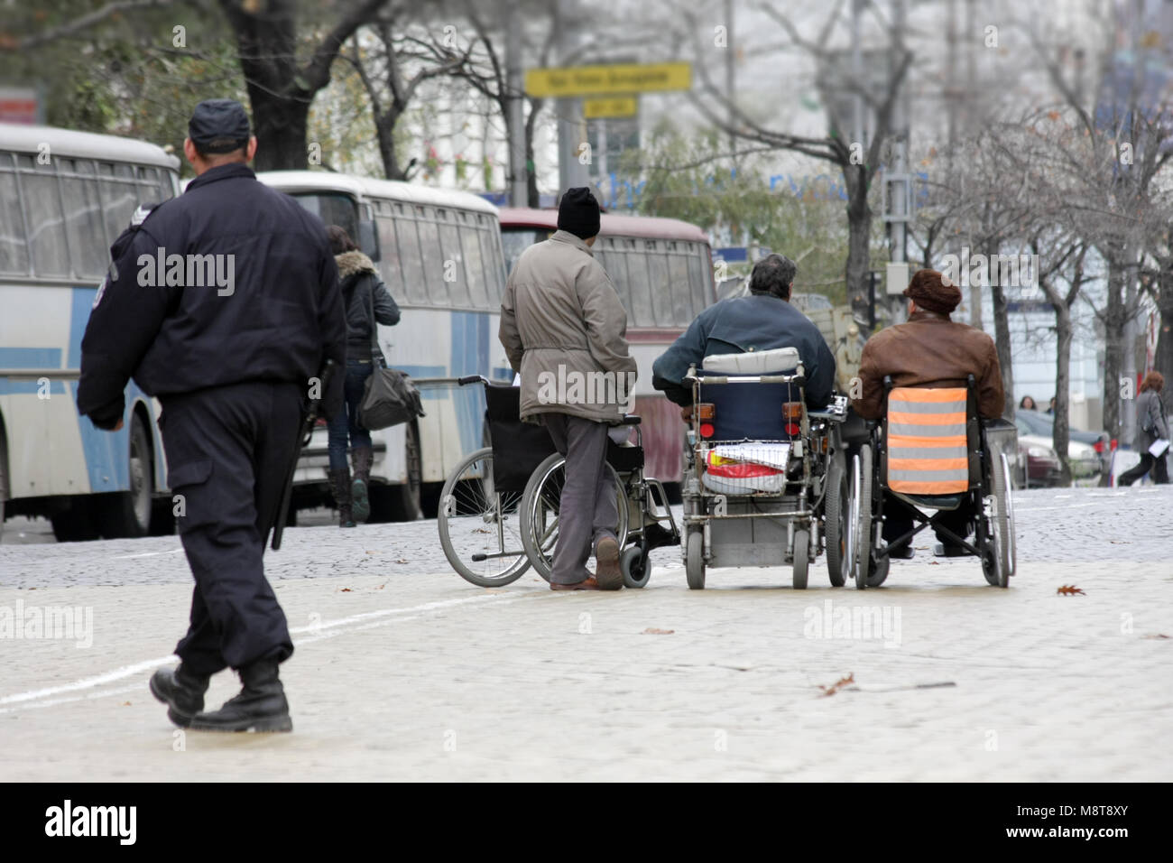 Handicapped people in wheelchairs on a street. Disabled person