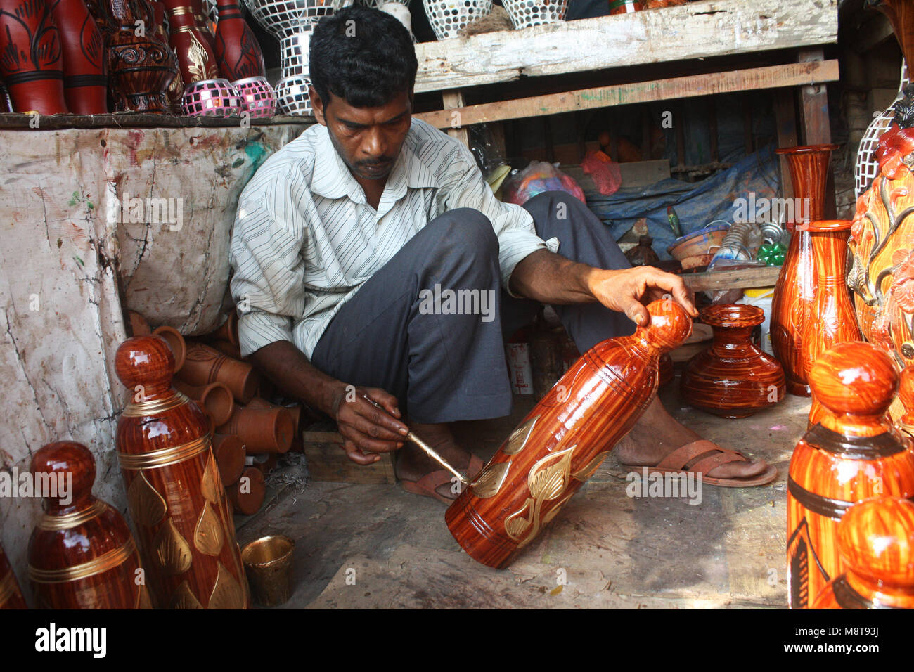 A shopkeeper paints the mud pot in his shop in Mud pots (Handicraft