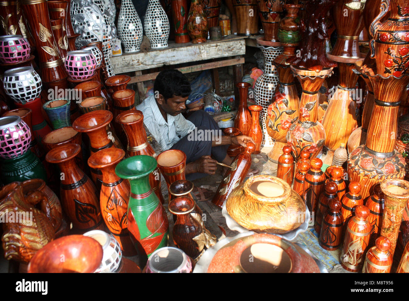 A shopkeeper paints the mud pot in his shop in Mud pots (Handicraft) market in Dhaka, Bangladesh.Different type of Mud pots (Handicraft) market in Dha Stock Photo