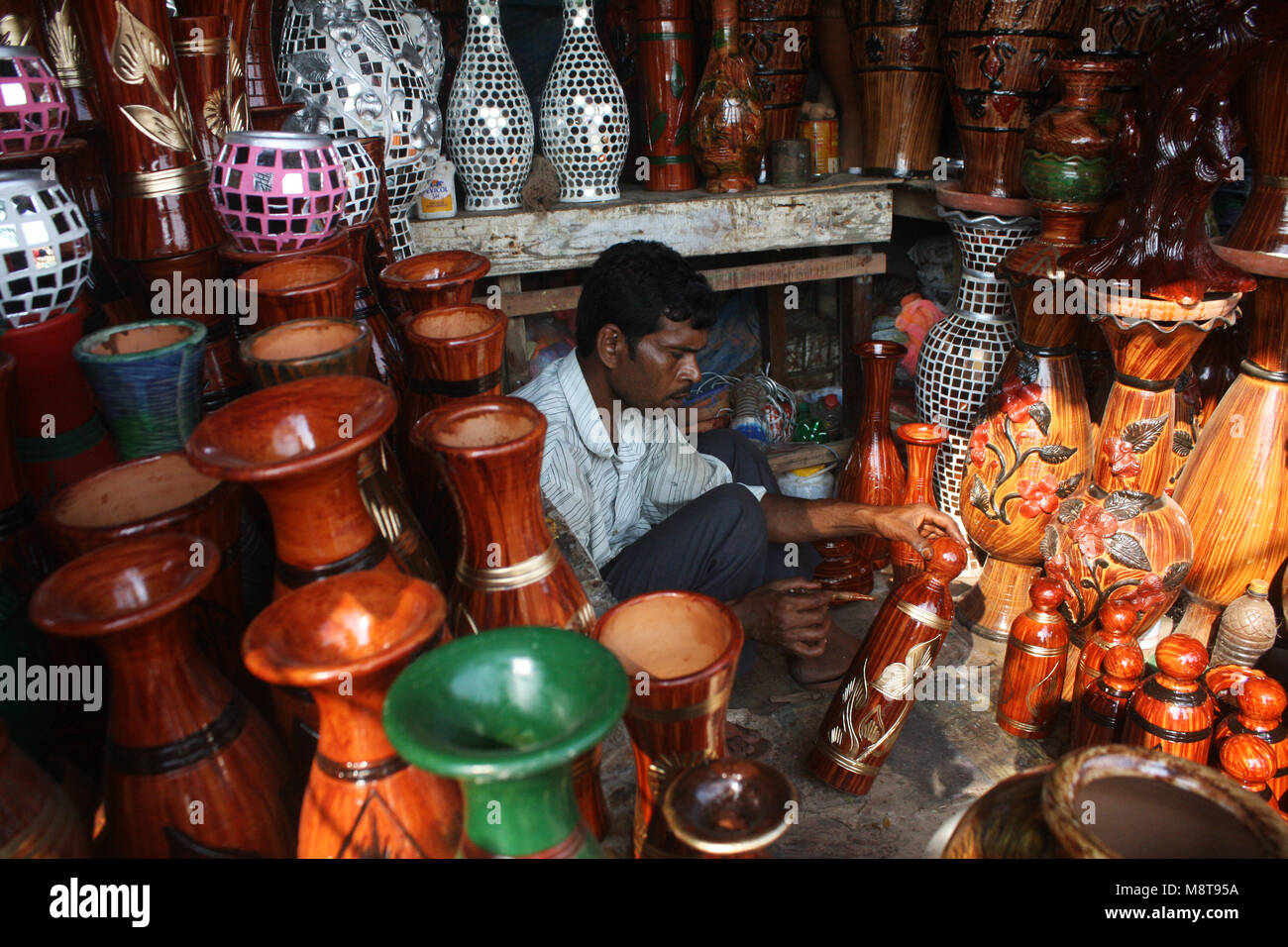 A shopkeeper paints the mud pot in his shop in Mud pots (Handicraft