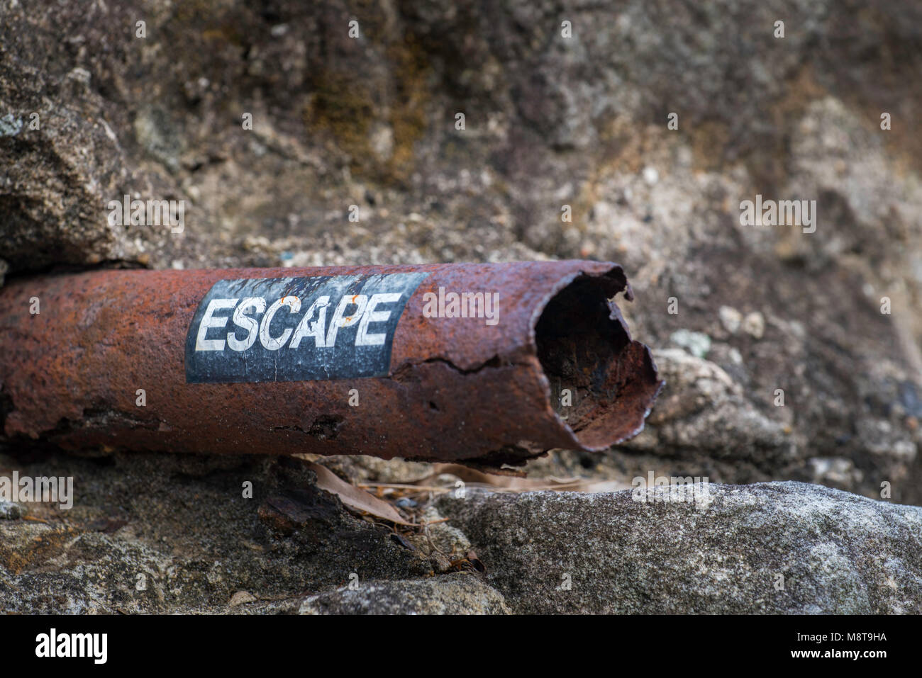 A clothing company advertising sticker or decal is virtually welded onto a rusty pipe protruding from a sandstone block wall in Pyrmont, Sydney, Aust. Stock Photo