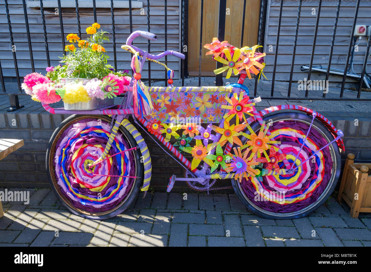 COLOURFULLY DECORATED  BIKE USED AS SALES PROP IN COURTYARD OF SMALL FARM SHOP, GLOUCESTERSHIRE UK Stock Photo