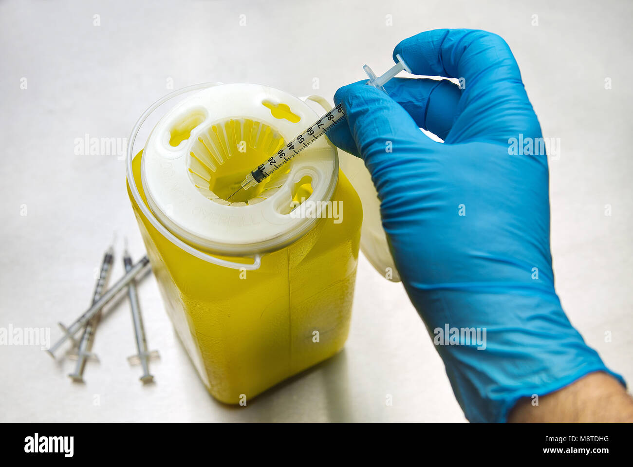 Montreal,Canada 18,March 2018.Gloved hand dispensing a used syringe in a medical container.Credit:Mario Beauregard/Alamy Live News Stock Photo