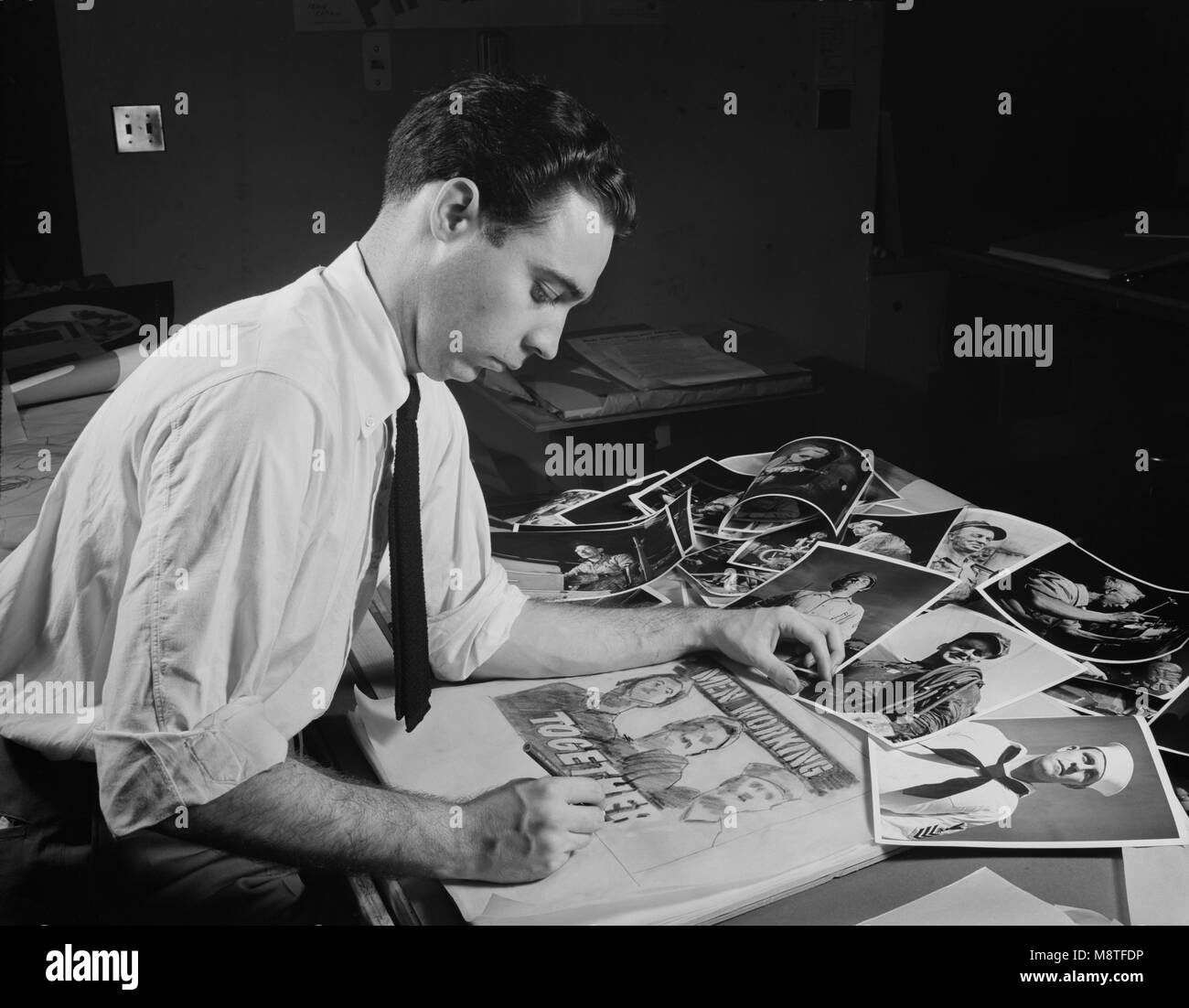 Office of War Information Artist Selecting Photographs to Create Rough Layout for Poster of  'Men Working Together', Washington DC, USA, November 1941 Stock Photo