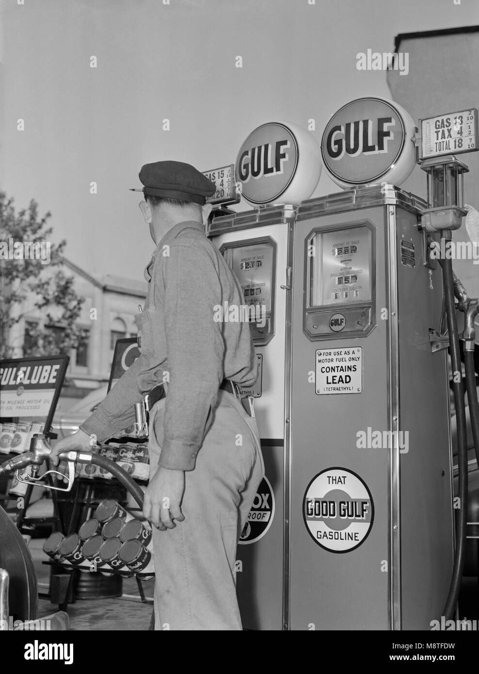 Gas Station Attendant Pumping Gas while Keeping an eye on Gauge during Gasoline Rationing, USA, Office of War Information, 1940's Stock Photo