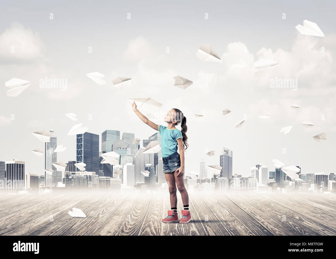Cute kid girl stand on wooden floor and paper planes flying around ...