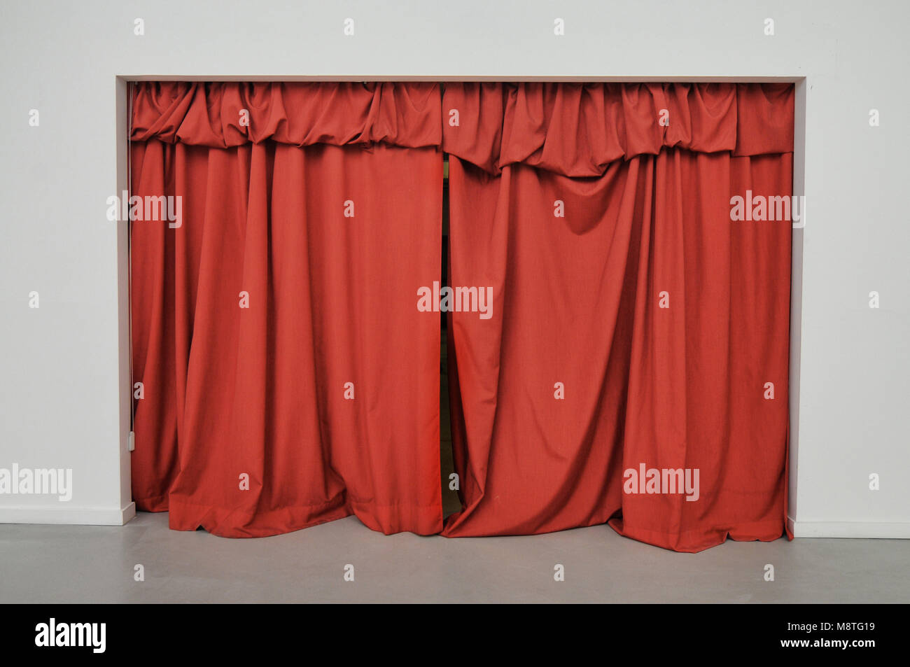 Red curtain closed over large doorway on a white wall Stock Photo