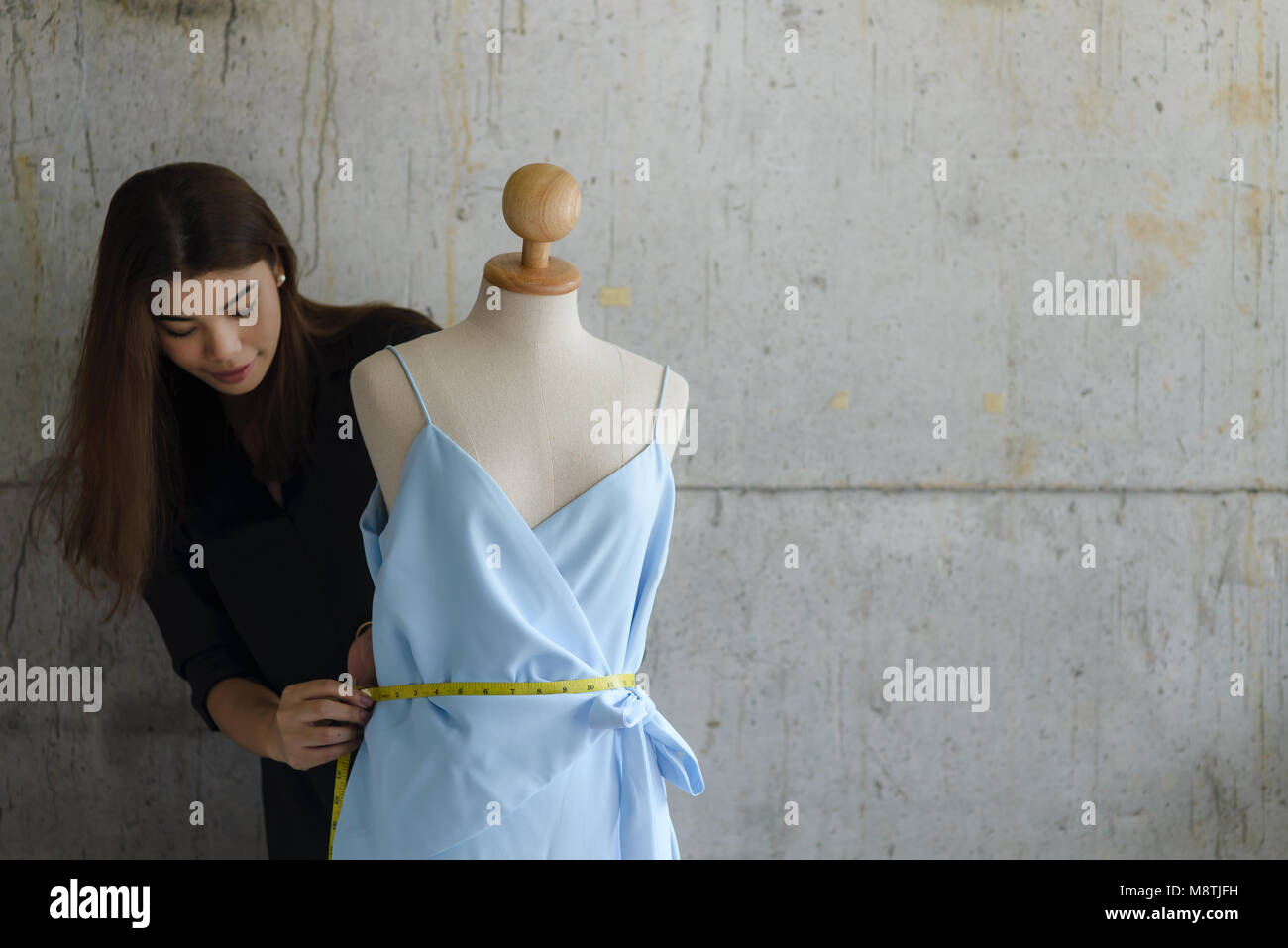 Asian female clothing designer using dress dummy, freelance lifestyle.  Selective focus. Stock Photo
