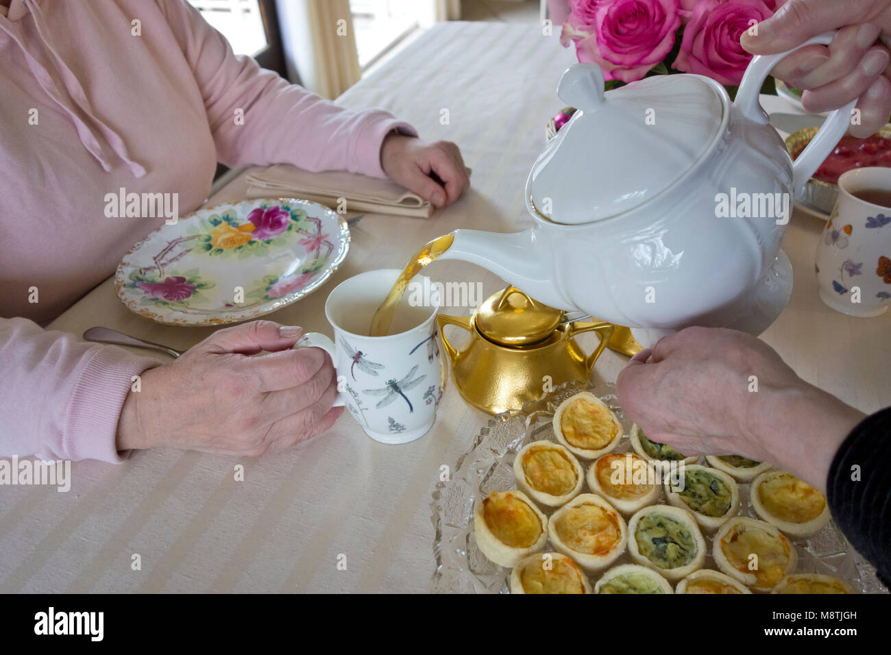 Two women friends having a cup of afternoon tea together.  Senior woman pouring a cup of tea for a friend during afternoon tea. Stock Photo