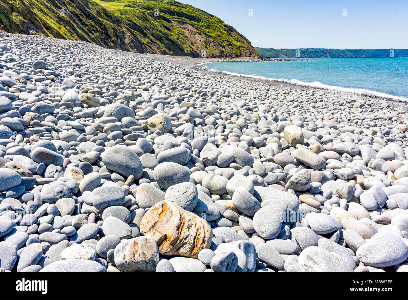 Greencliff Beach - Pebble View at Mid Tide, Looking South West towards Bucks Mills (Low angle, landscape view): Greencliff Beach, near Bideford, Devon Stock Photo