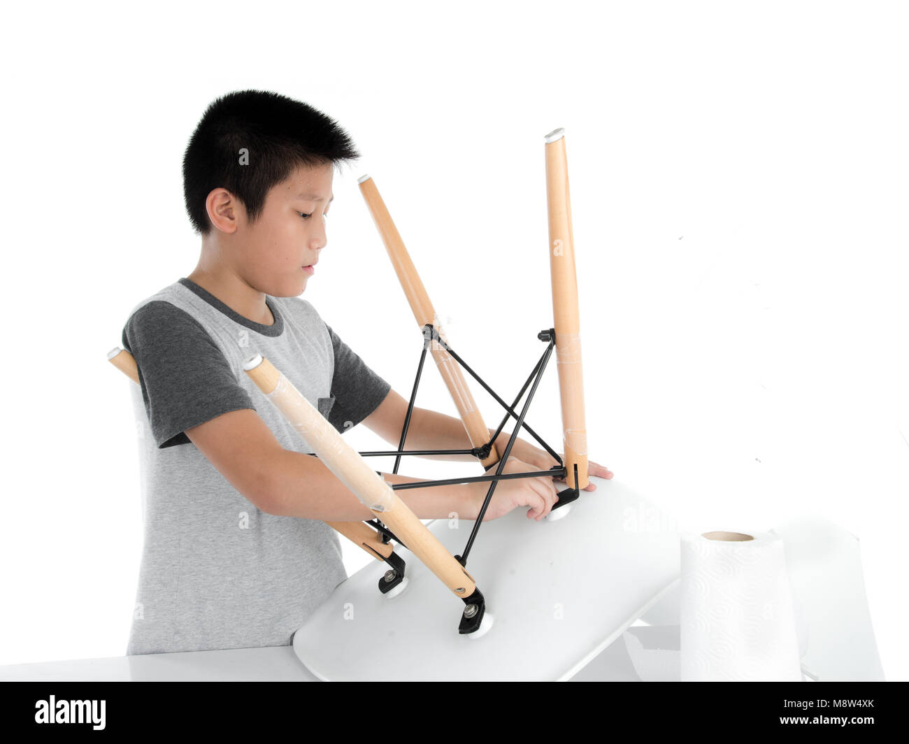 Asian boy repair leg chair on white backgorund. Stock Photo