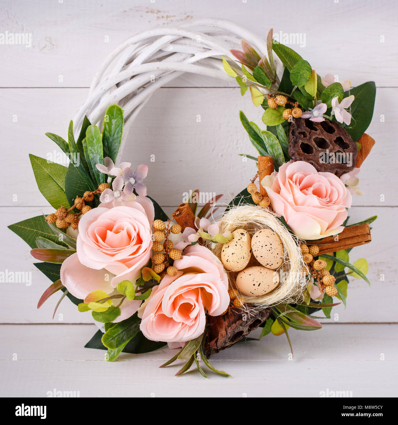 Decorative woven wreath is decorated with flowers and quail eggs. Wreath for pecker's Easter holidays Stock Photo