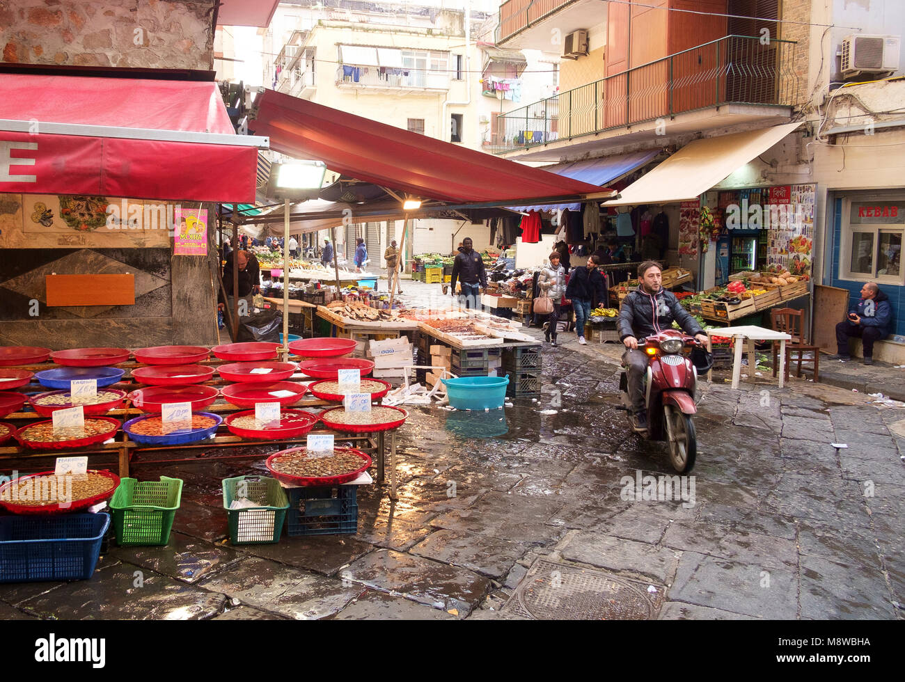 A motor cyclist negotiates Via Sopramuro - the food market street near Porta Nolana, Naples Stock Photo