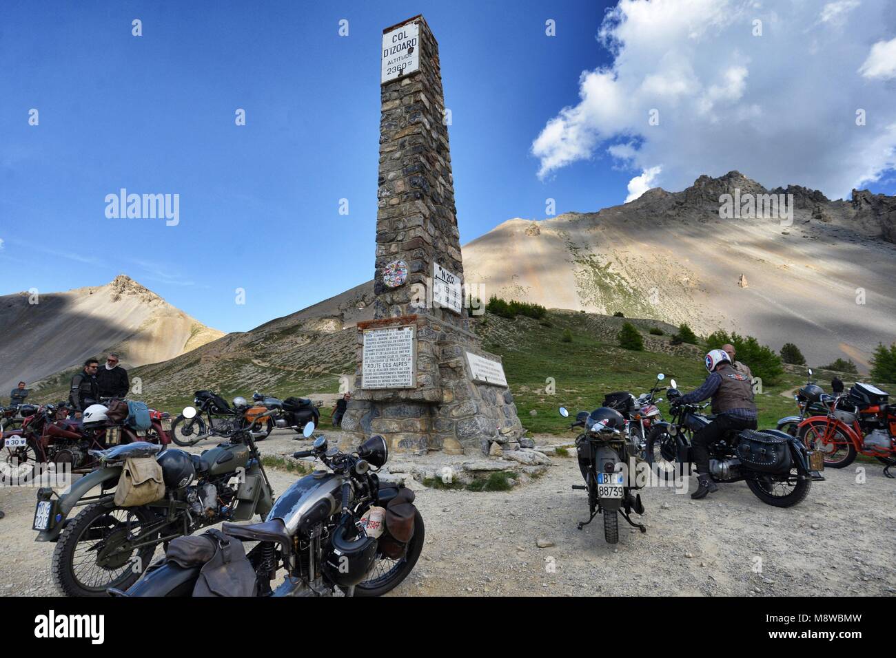 Group of vintage motorbike rider layover front view in mountain landscape with cloudy sky France Alps Izoard hill pass circa June 2015 Stock Photo