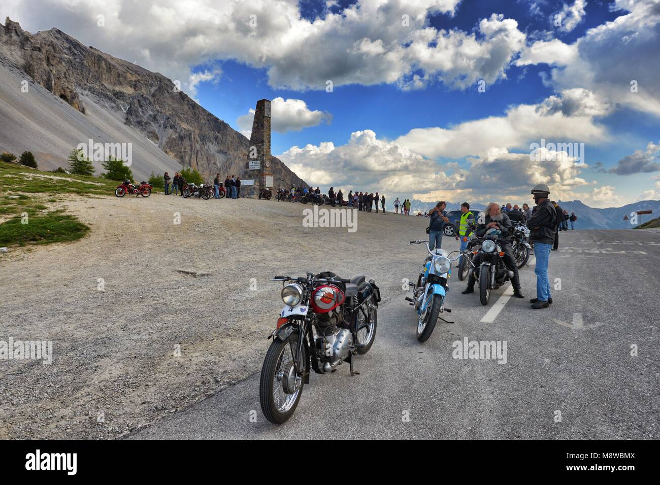 Group of vintage motorbike rider layover front view in mountain landscape with cloudy sky France Alps Izoard hill pass circa June 2015 Stock Photo