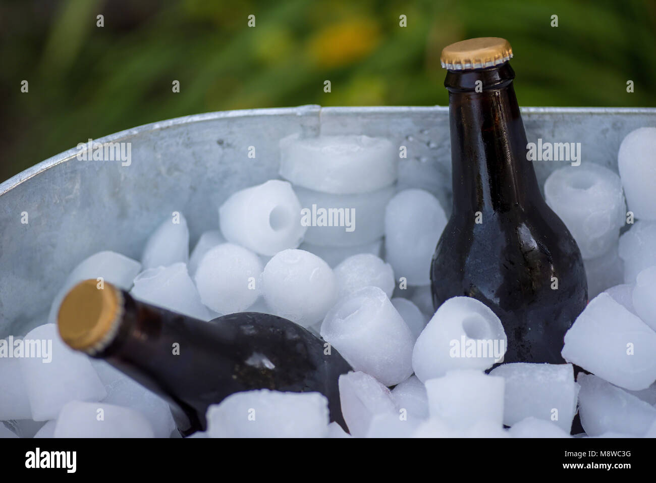 closeup of brown beer bottles in galvanized tub with ice cubes in summer Stock Photo
