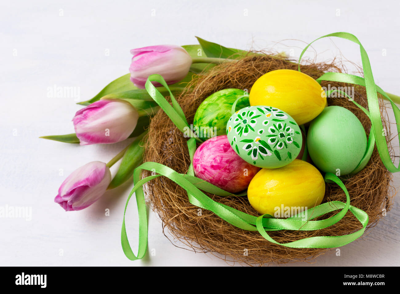 Easter background with green and yellow painted eggs in the nest and ...