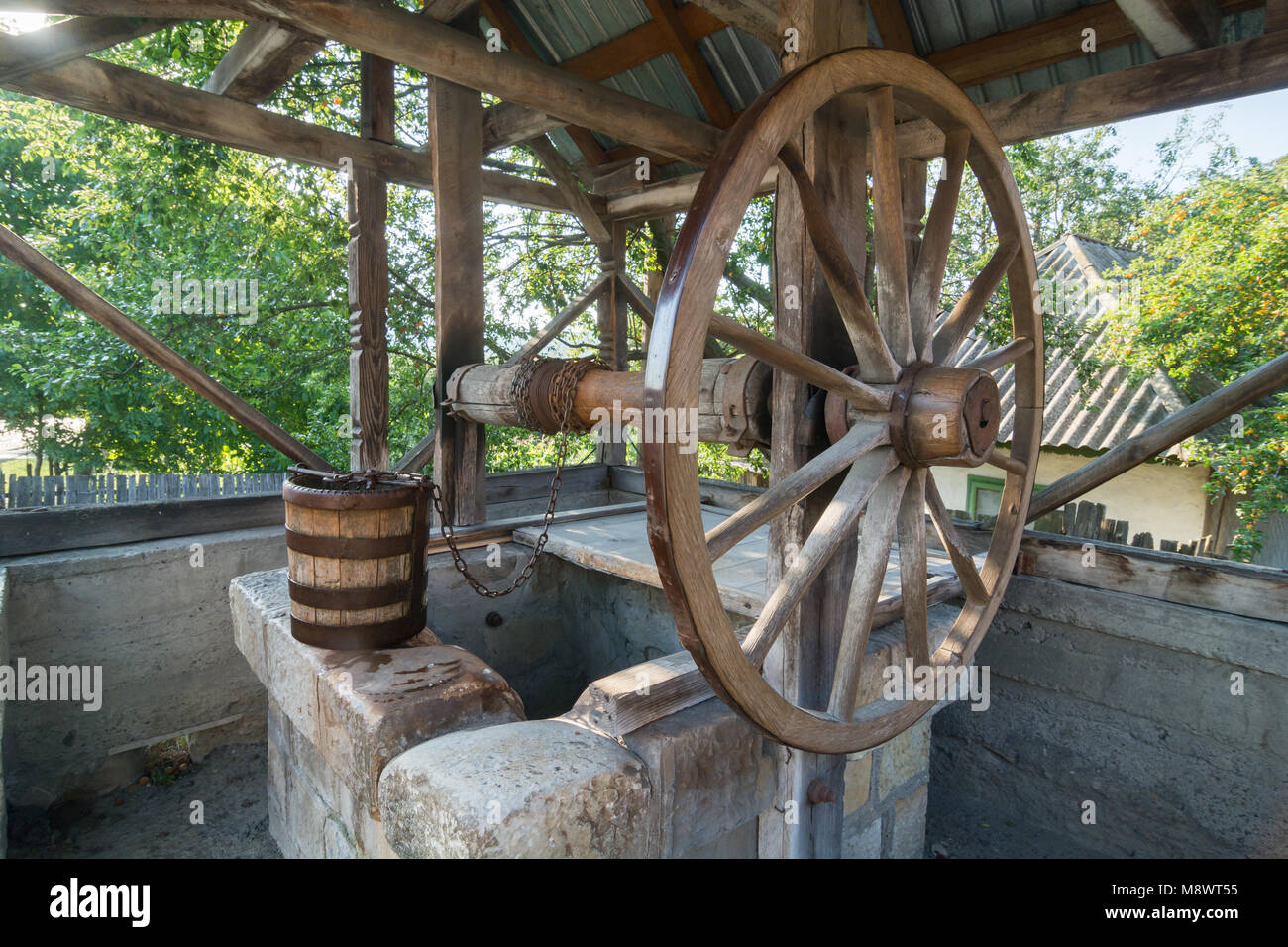 Old,traditional, wooden well with a large wheel, chain and bucket in the country side of Romania Stock Photo