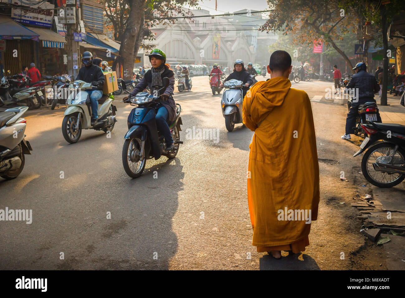 Vietnam street scene, view at daybreak of a young Buddhist monk making his way through the historical Old Quarter in the centre of Hanoi, Vietnam Stock Photo